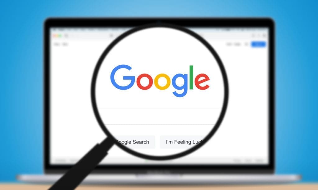 A magnifying glass over the google logo on a laptop.