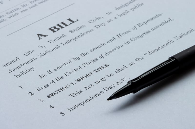 A close-up of a document titled "A BILL" with the text referencing the "Juneteenth National Independence Day Act," and a black pen resting on the page.