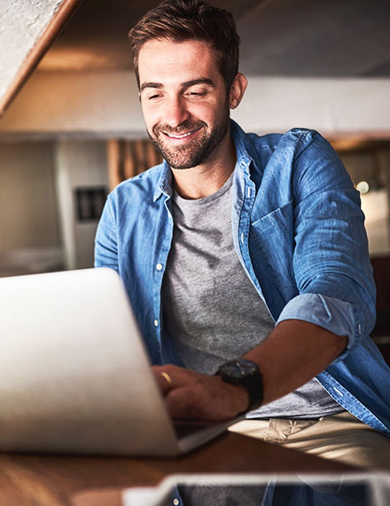 young man smiling on his laptop