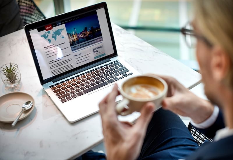 A man is sitting at a table with a laptop, diligently working on restoring his online reputation.