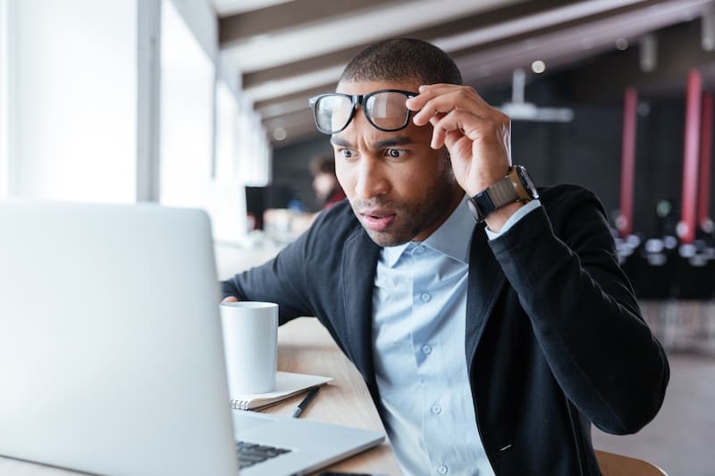 A man wearing glasses is researching how to remove articles from the internet on his laptop.