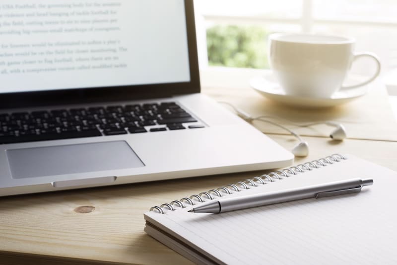 A laptop and a cup of coffee on a wooden table.