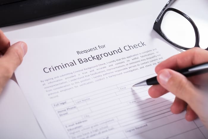 A hand holding a pen over a paper for mugshot removal documentation.