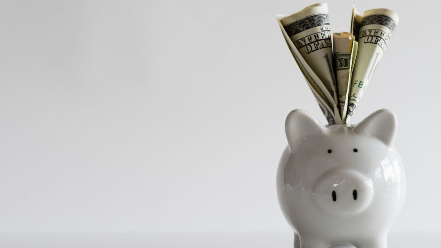 A piggy bank with dollar bills sticking out of it.