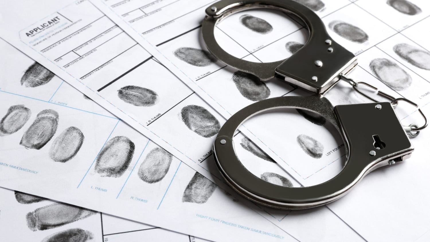 Handcuffs and fingerprints on a sheet of paper.