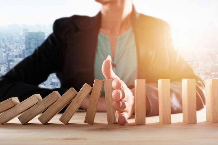 A reputation management consultant is holding a domino in front of a wooden table.