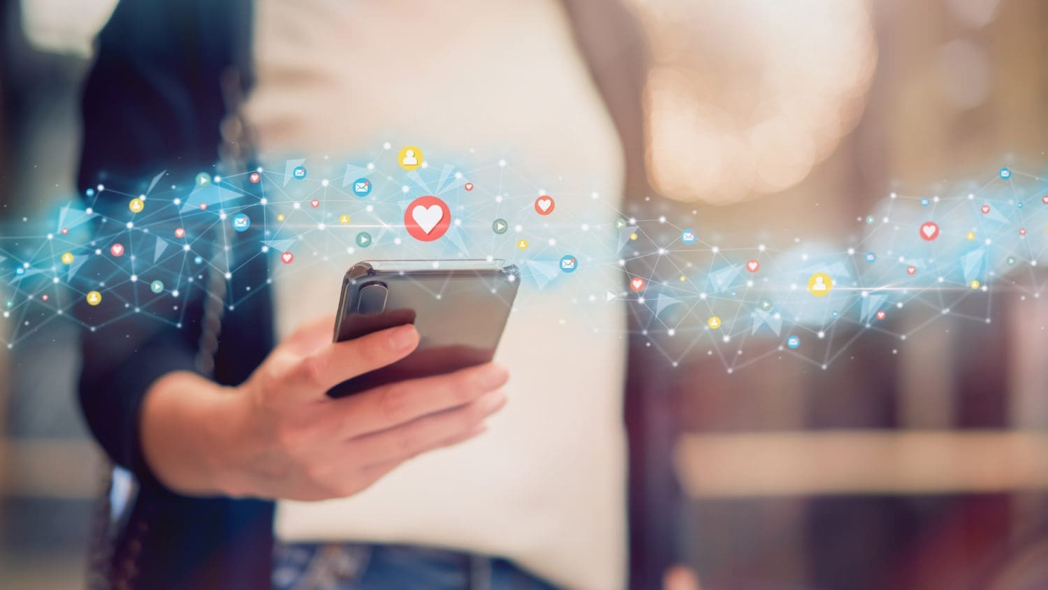 A woman is holding a cell phone with social media icons on it.