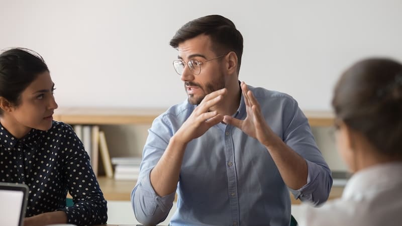 A group of people sitting around a table in a meeting discussing the need for online reputation management.