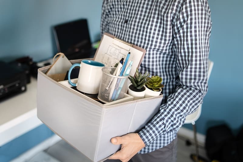 A man carrying a box full of office supplies while attempting to restore online reputation.