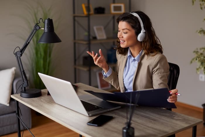 A woman wearing headphones is sitting at a desk with a laptop, seeking assistance from reputation management consultants.