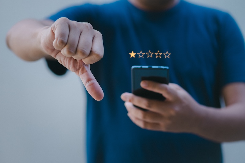 A man holding a smartphone with a star rating on it, helping to restore online reputation.