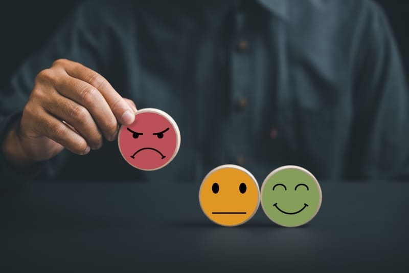 A man is holding two different colored emoticons, attempting to restore his online reputation, on top of a black background.