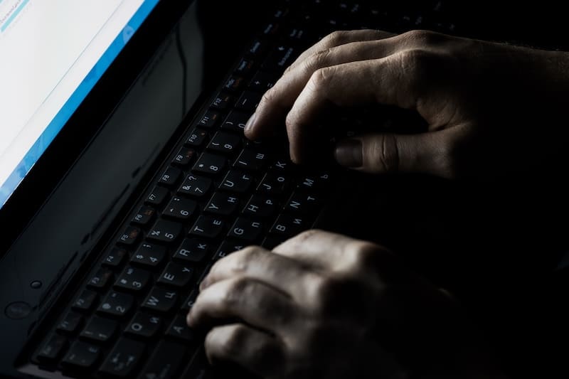 A person's hands type on a keyboard to find out, "What is the dark internet?"
