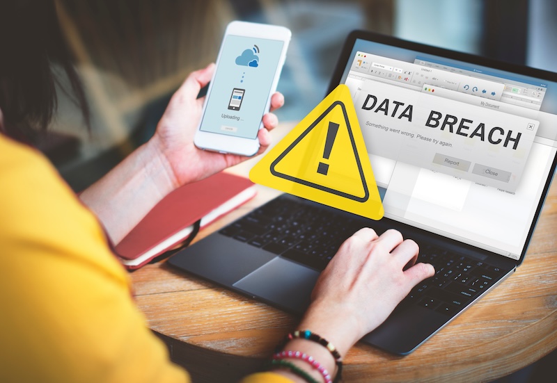 A person receives a data breach notification on a laptop screen while holding a smartphone, highlighting the importance of cybersecurity for Florida residents in the directory opt-out process.