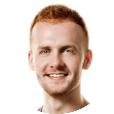 A young man with short, reddish hair and a trimmed beard is smiling at the camera. The background is white, and the image is framed in a circular crop, making him look like a friendly team member ready to connect.