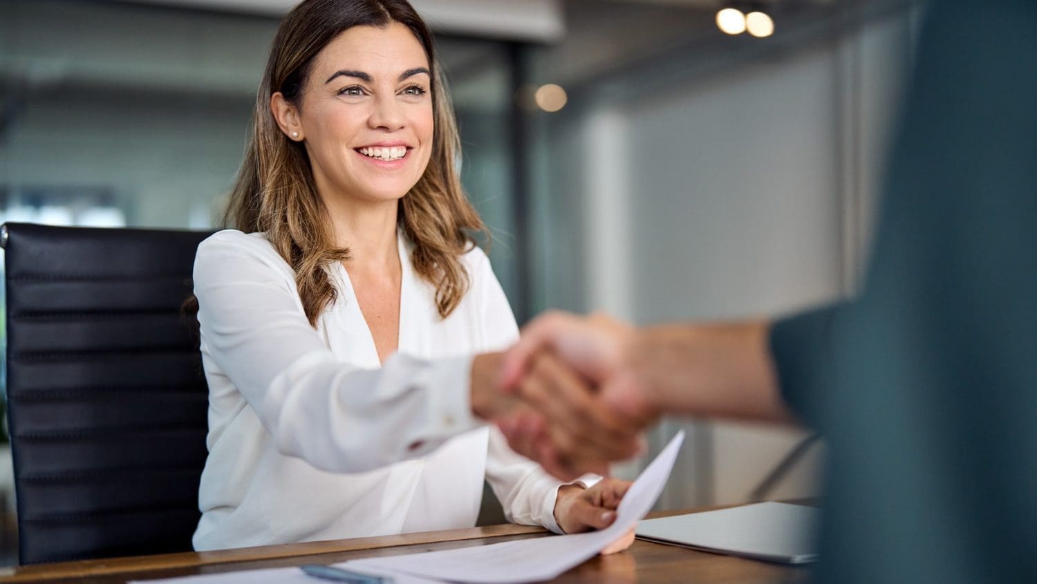 A woman shaking hands with a man at a desk in the presence of reputation management consultants.