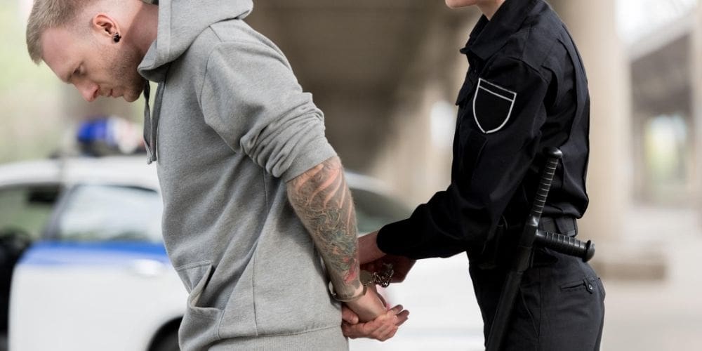 a police officer helping a man with his hand.