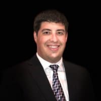 a man in a suit and tie smiling at the camera.