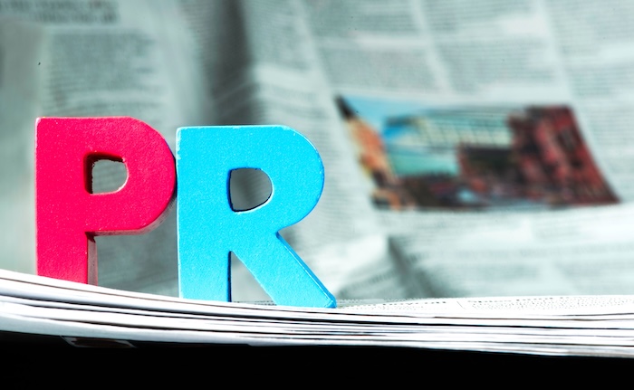 The word "pr" is prominently spelled out on top of a newspaper, symbolizing the important role of company reputation management.