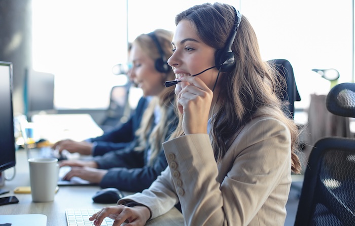 Two women managing company reputation in a call center with headsets on.