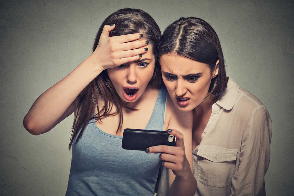 two women shocked looking on a phone