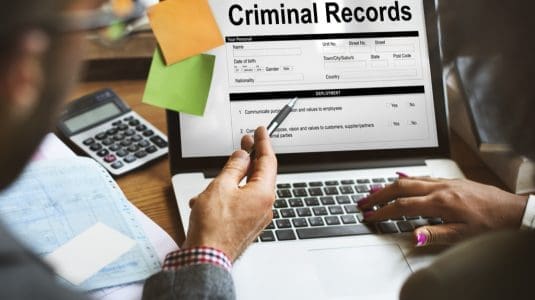 laptop with posted notes showing criminal records