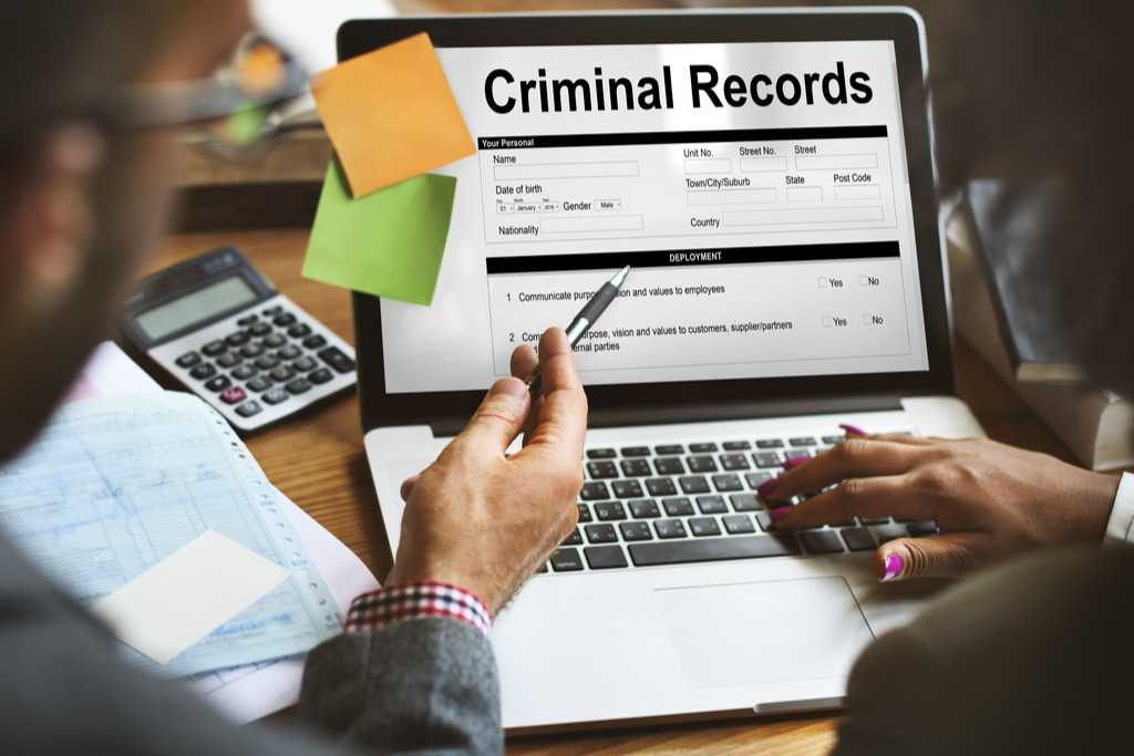laptop with posted notes showing criminal records