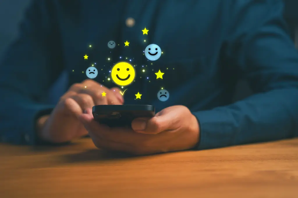 A person using a smartphone with cheerful, neutral, and sad emoji faces and yellow stars floating above the screen, symbolizing feedback or rating.