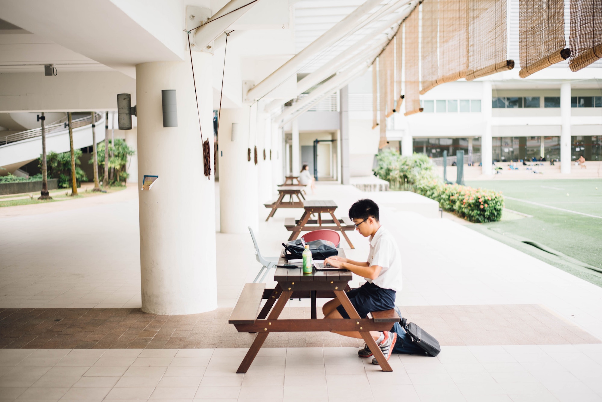highschool boy on laptop sitting at a bench