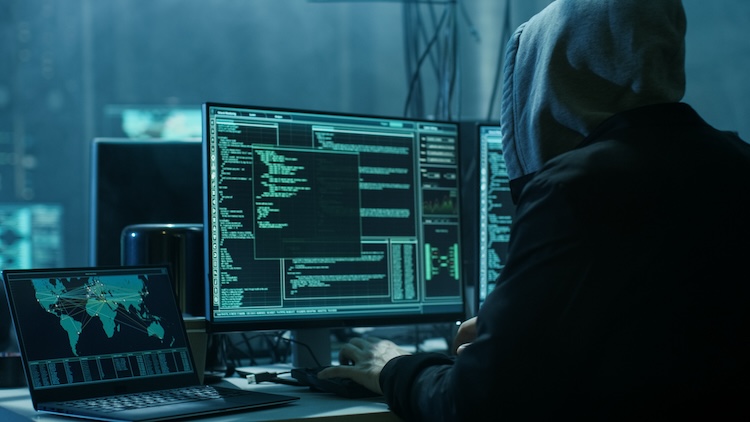 A hooded figure engages in cyber activities to eliminate unwanted Google search results in a dimly lit room filled with computer monitors displaying lines of code and a global network map.