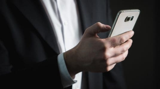 man in suit holding smartphone