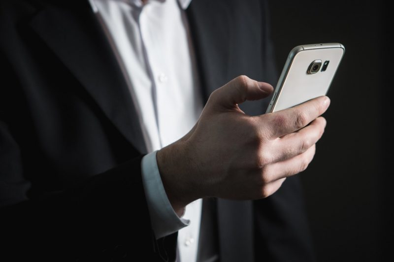 man in suit holding smartphone