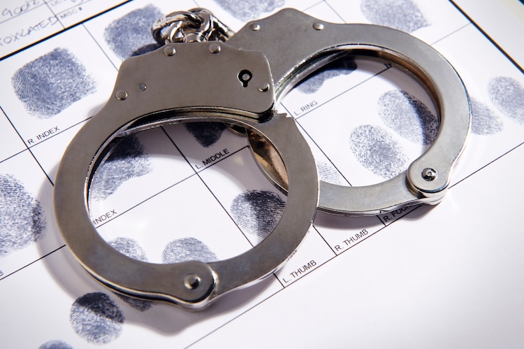 Handcuffs resting atop a fingerprint identification sheet, symbolizing law enforcement and the challenges of unwanted google search results in criminal investigation.