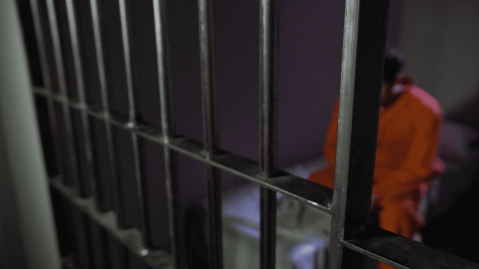 a jail cell with a person in the background.