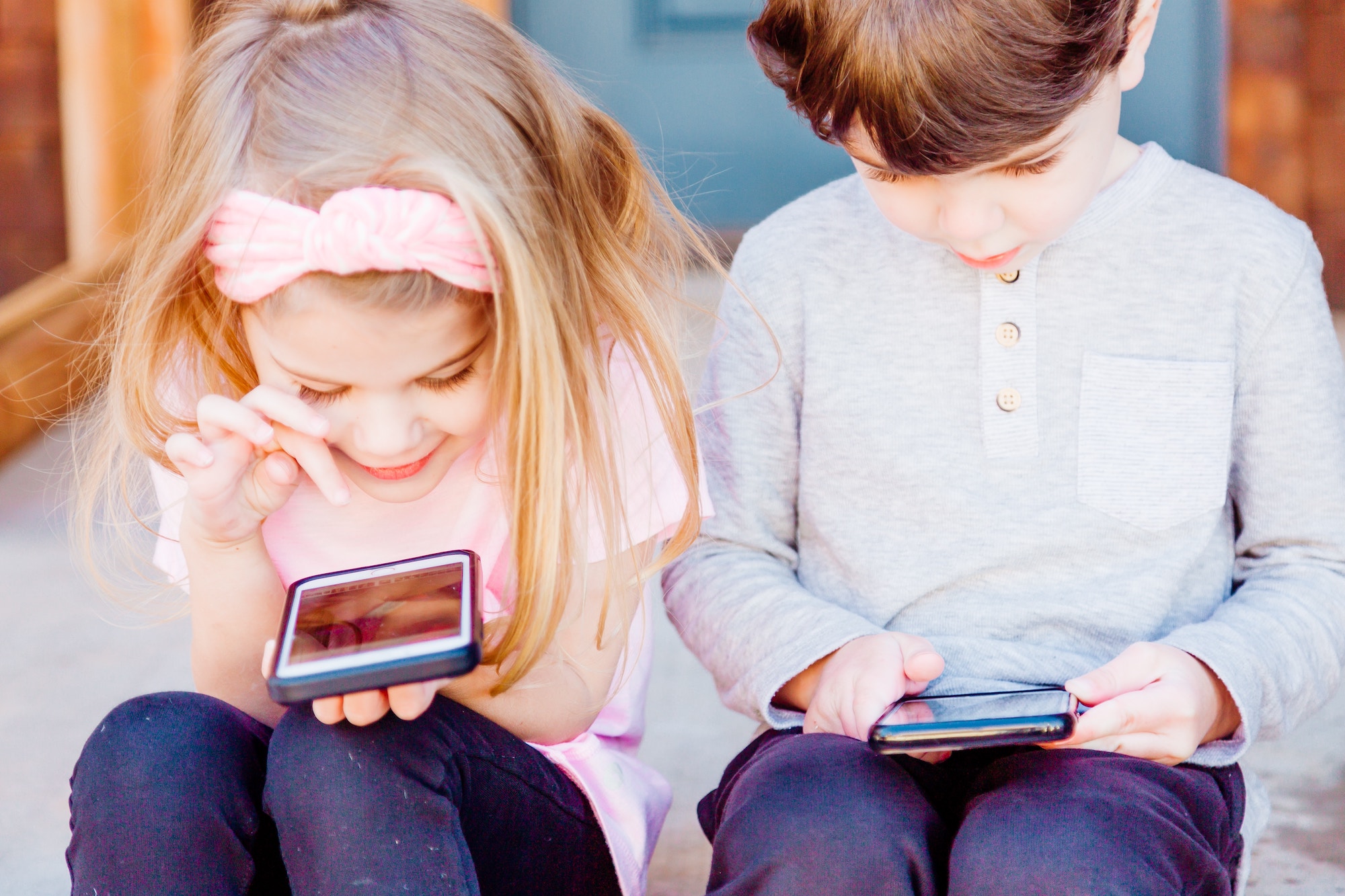 young girl and boy playing on smartphones