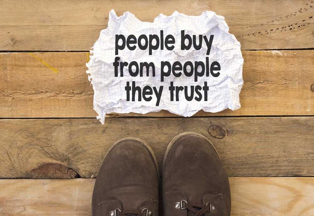 people buy from people they trust on crumbled paper with shoes