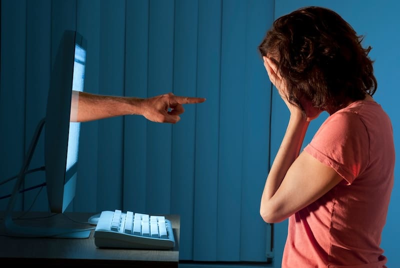 A woman is pointing her finger at a computer screen.