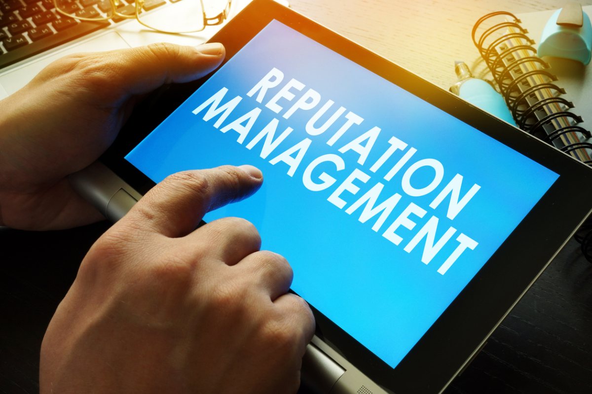 a person holding a tablet with the words reputation management on it.
