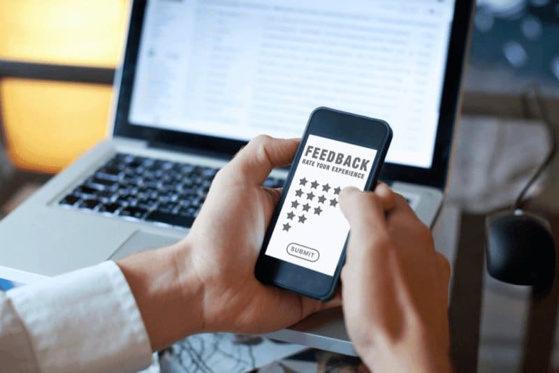 a person holding a cell phone in front of a laptop.