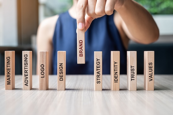 A person aligning wooden blocks inscribed with various words related to what makes a brand strong and other marketing concepts.