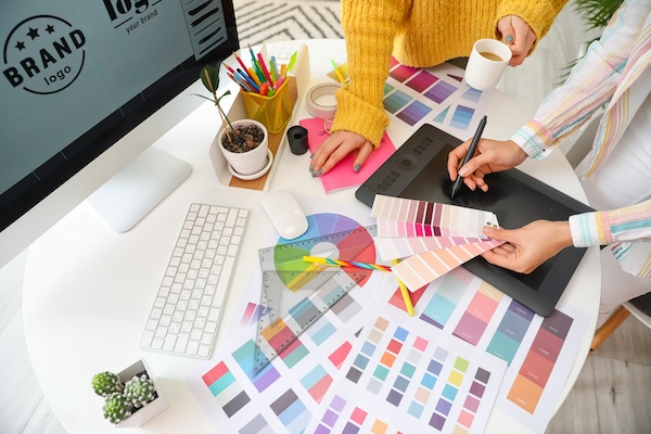 Graphic designer at work with color samples and a drawing tablet, focusing on what makes a brand strong.